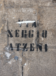 Pintada en un carrer de Càller. S'hi llegeix «Via Sergio Atzeni», i algú hi ha ratllat al damunt la paraula en italià.