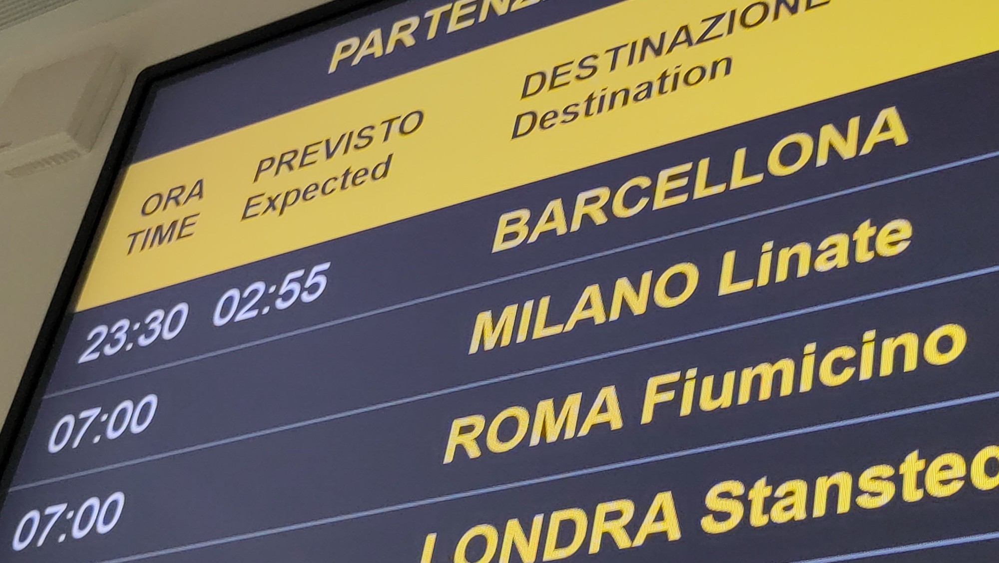 Pantalla d'aeroport que mostra un retard de més de tres hores al vol de Barcelona.